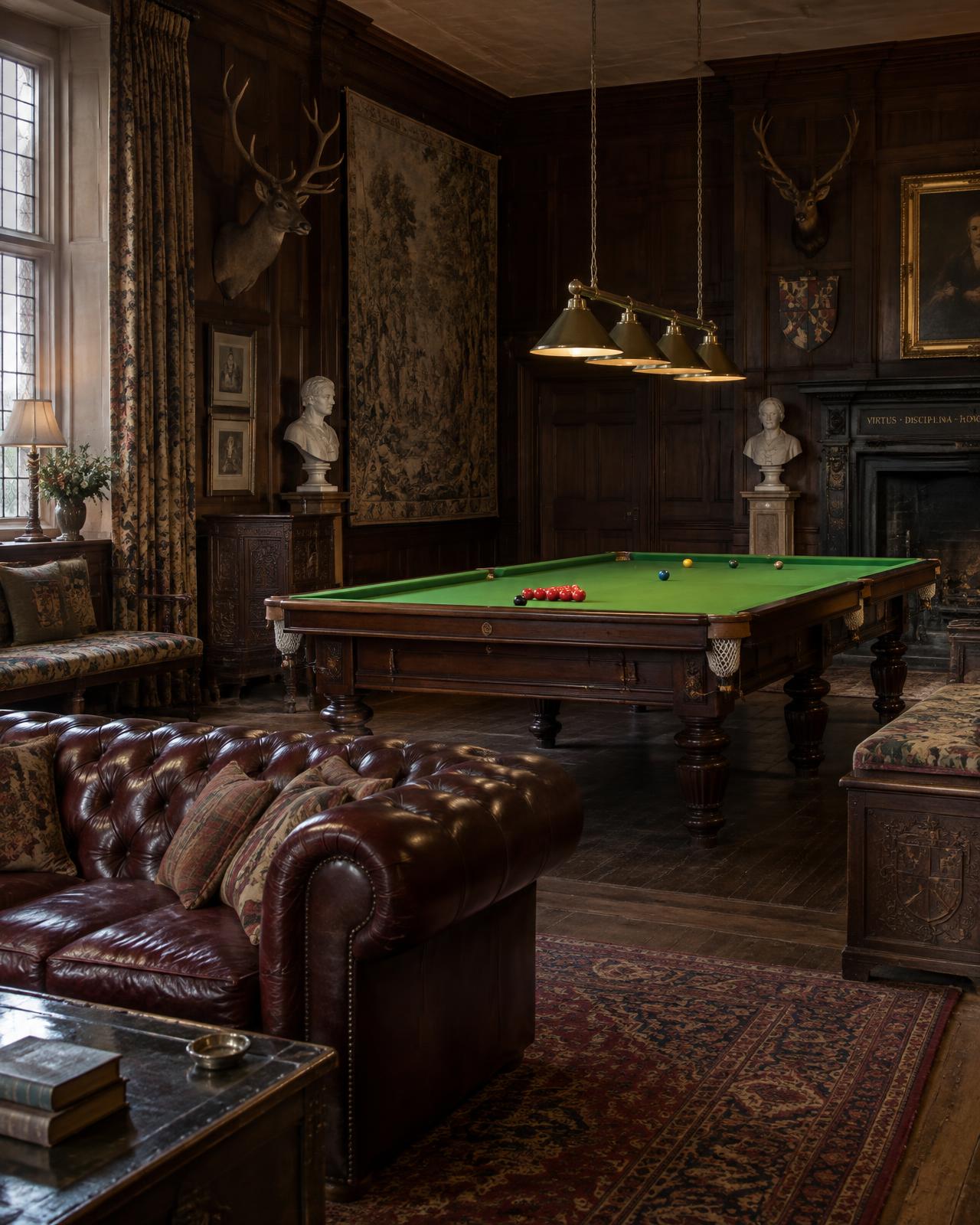 A panelled billiard room with a snooker table, a leather Chesterfield, antlers, marble busts, armorial chests and a tapestry